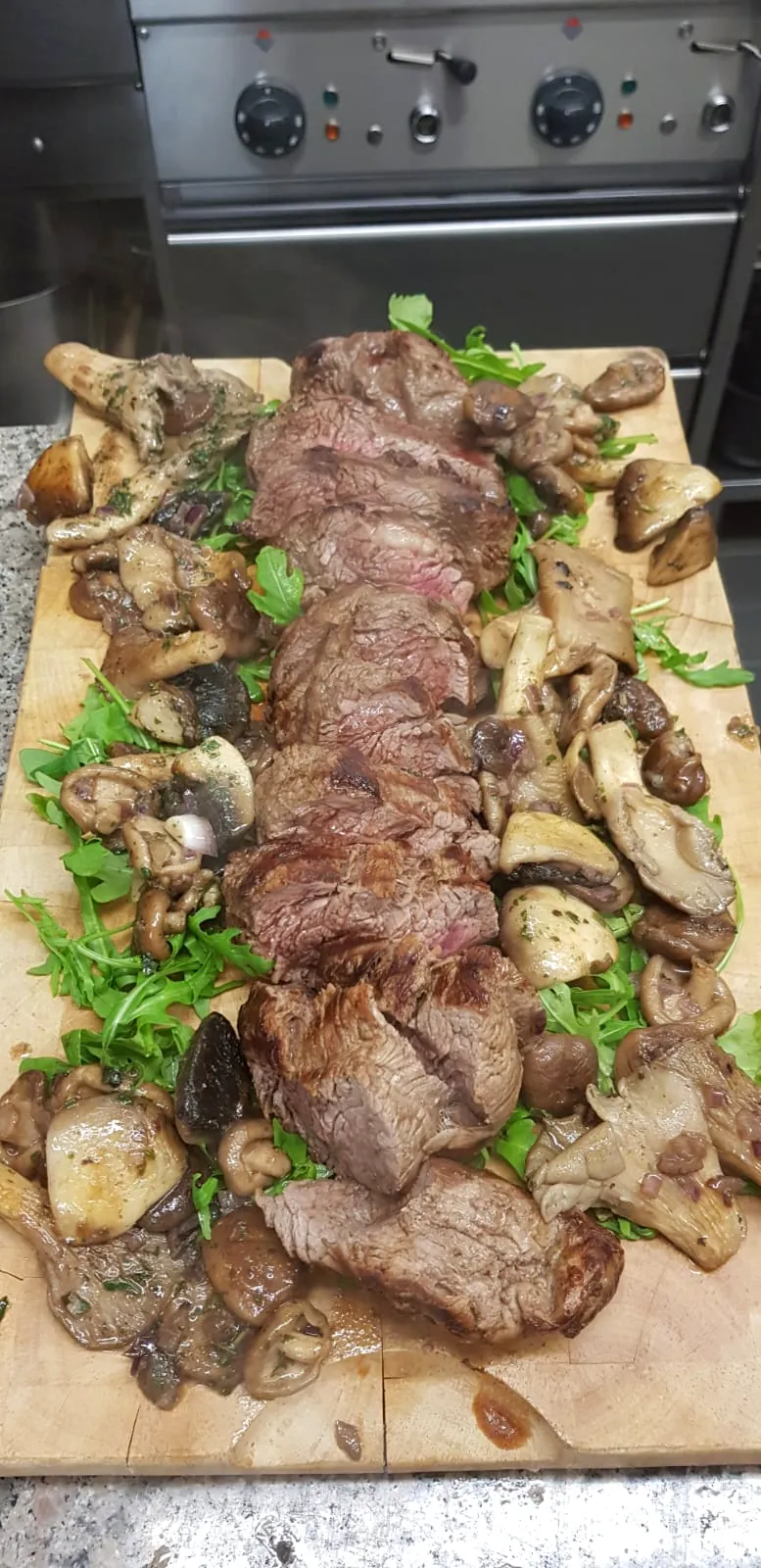 Rinderbraten in Scheiben mit gebratenen Pilzen auf dem Holzbrett